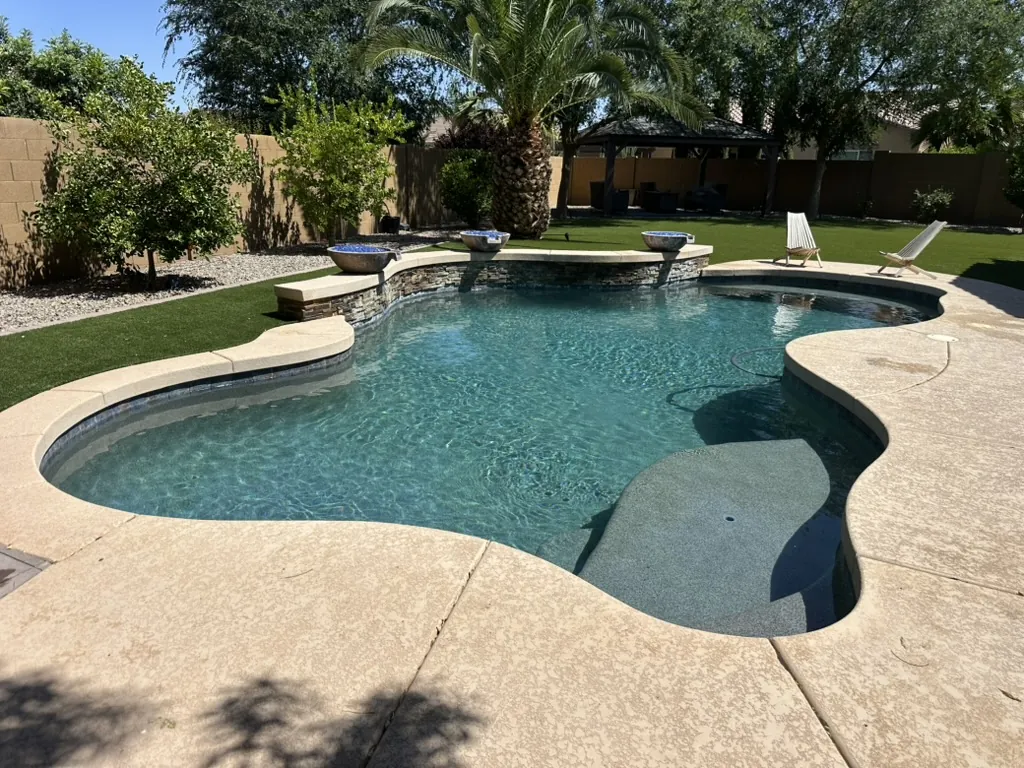 Freeform pool with fire bowls and turf